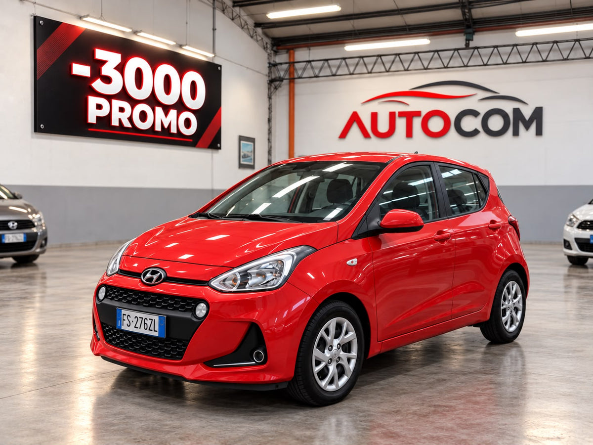 Hyundai i10 Prime rossa, vista anteriore di tre quarti nello showroom AUTO-COM a Torino