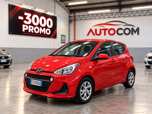 Hyundai i10 Prime rossa, vista anteriore di tre quarti nello showroom AUTO-COM a Torino